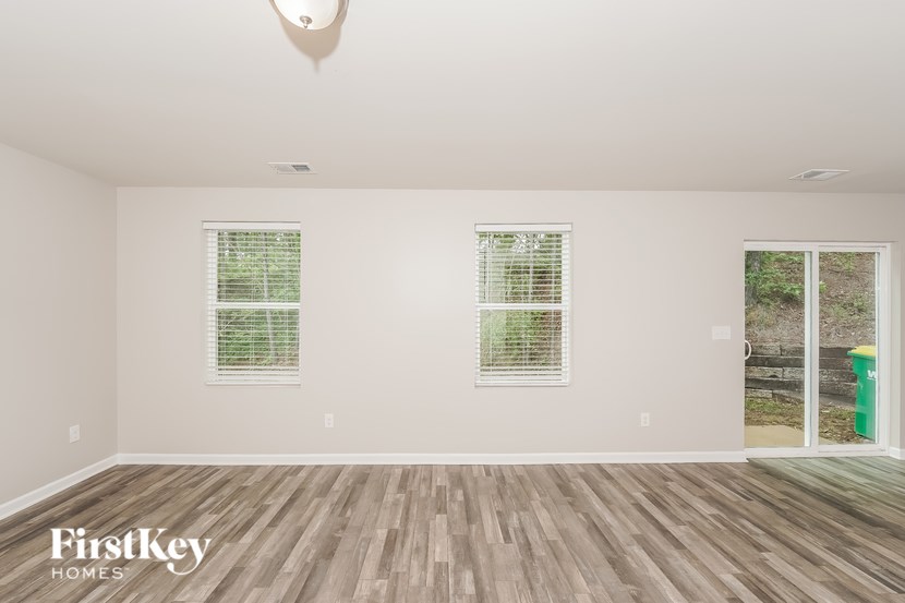 A room with wooden floors and two windows with blinds.
