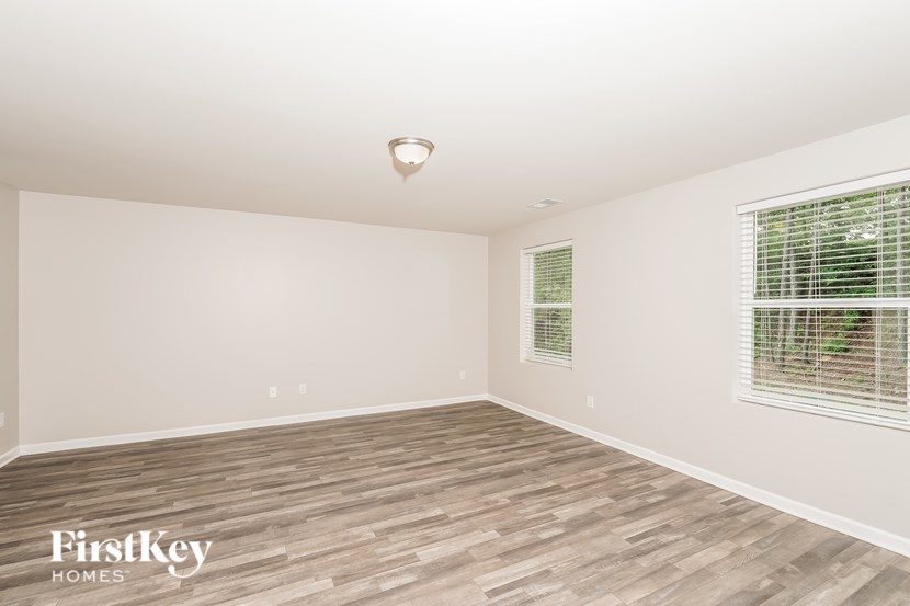 A room with wooden flooring and a window with blinds.
