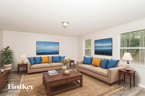 A living room with a beige couch, a coffee table, and a painting on the wall.