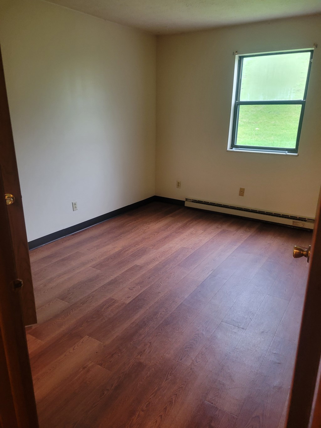 A room with a window and wood flooring.