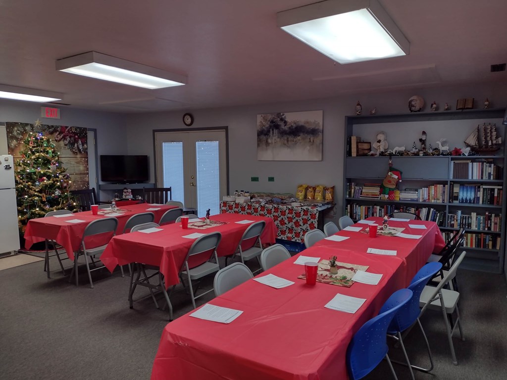 A room with tables covered in red cloth and chairs around them.