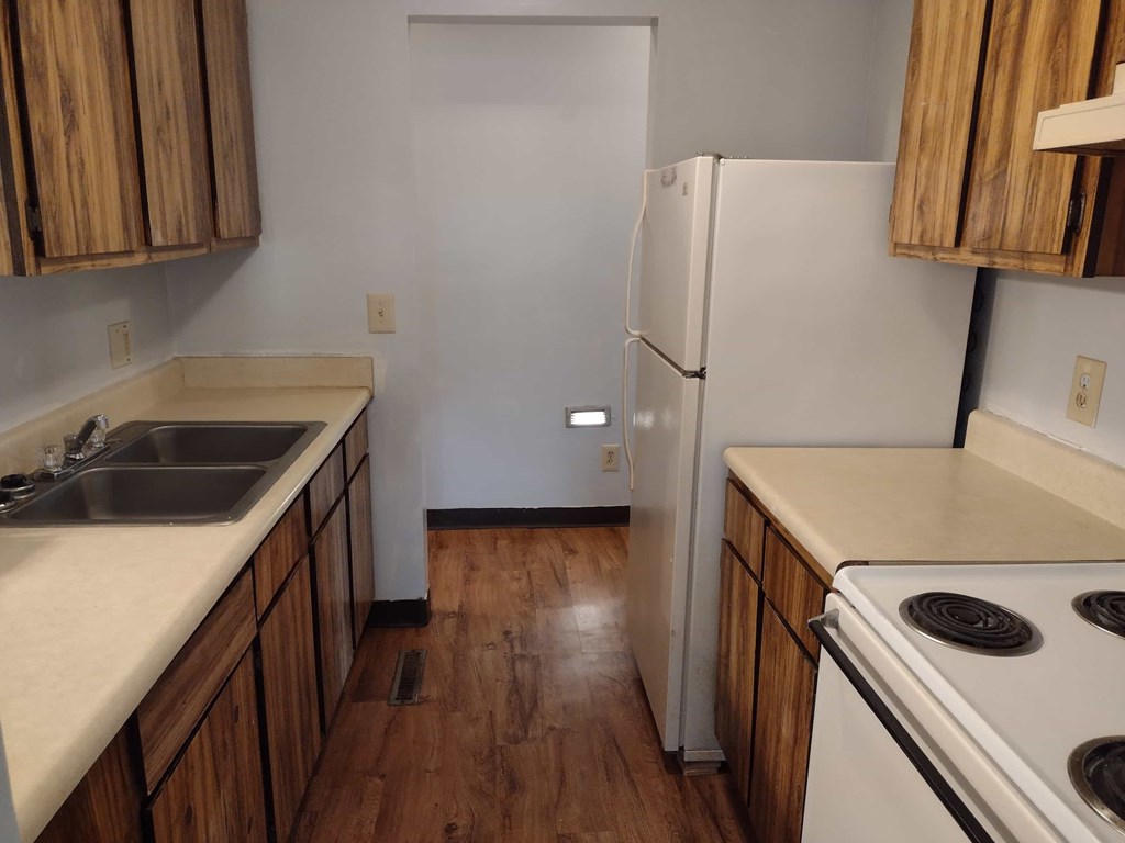 A kitchen with a white fridge and wooden cabinets.