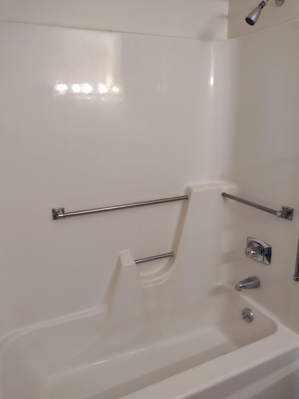 A white bathtub with a shower head and faucet.