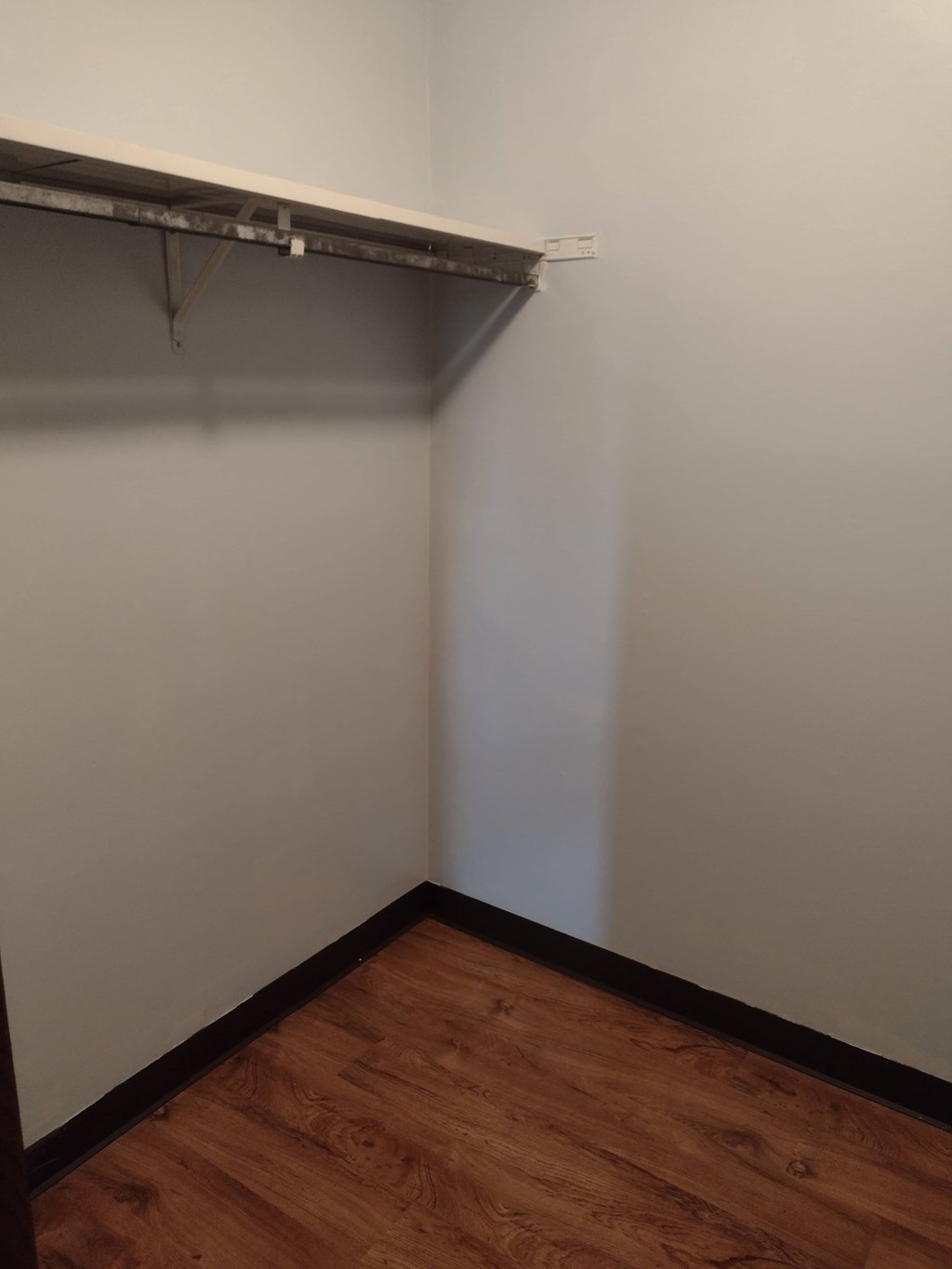 A white wall with a wooden floor and a white shelf.
