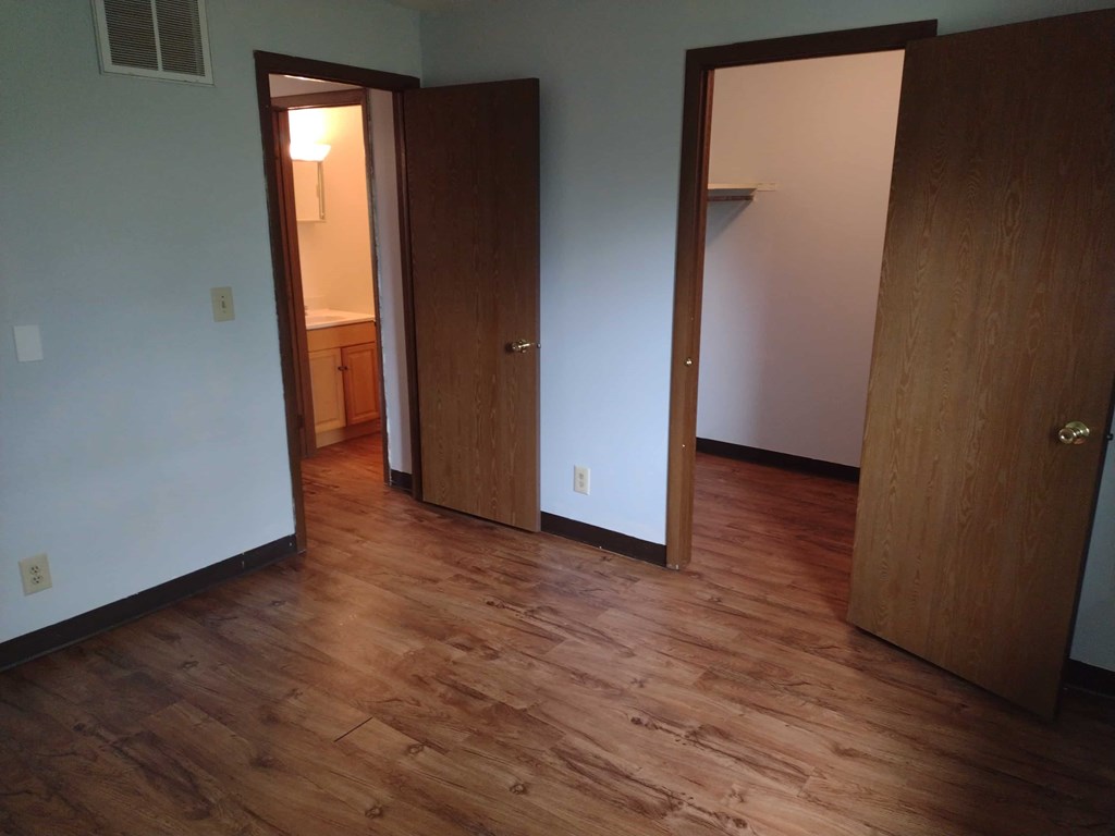 A room with wood floors and two doors.