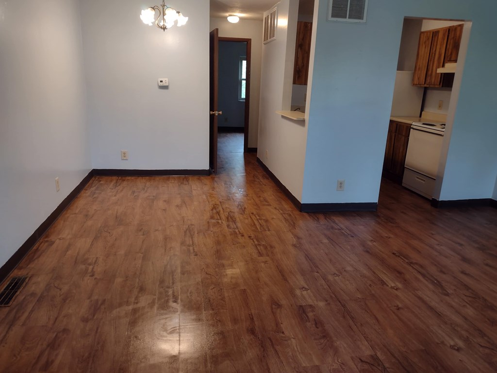 A room with wooden floors and a door leading to another room.