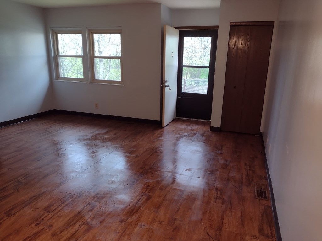 A room with a brown wooden floor and a door.