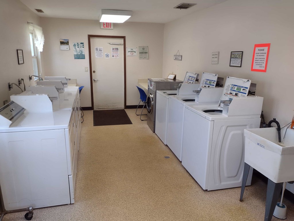 A clean, white-walled room with a row of washing machines and a door marked "EXIT".