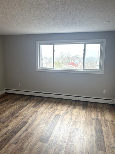 A room with a large window and wooden flooring.