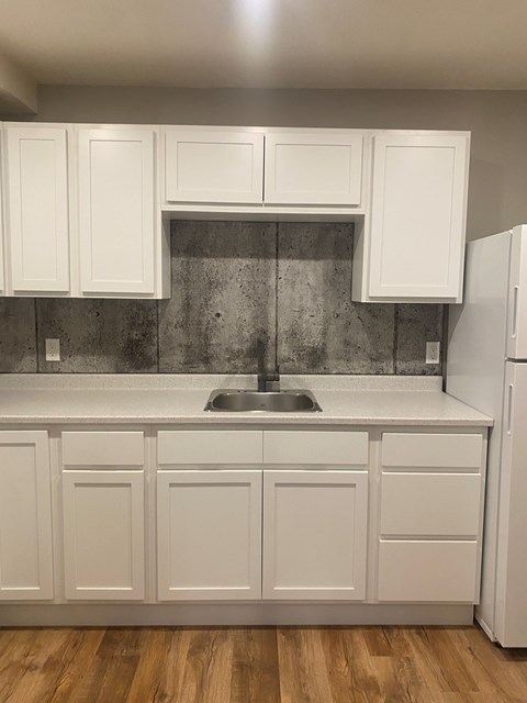 A kitchen with white cabinets and a wooden floor.