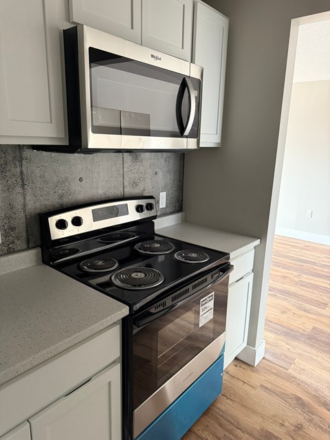 A modern kitchen with a stove and microwave above it.