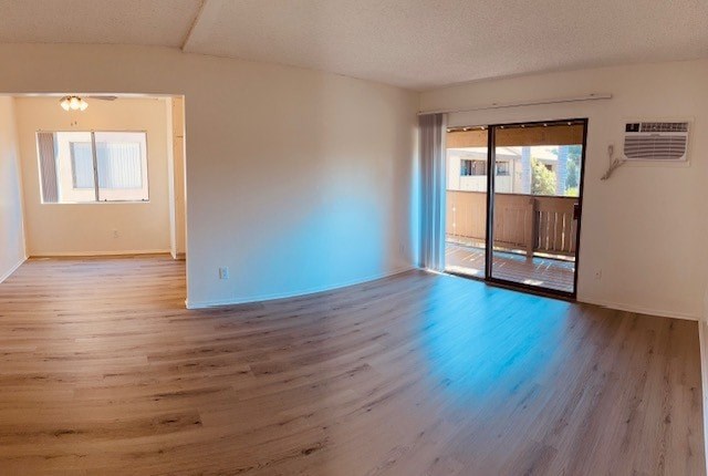 A room with wooden floors and a sliding glass door leading to a balcony.