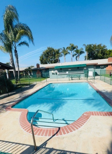 A pool surrounded by a fence and palm trees.