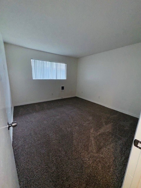 A room with a carpeted floor and a window with blinds.