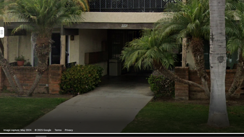 A concrete pathway leads to a building with a glass door and windows.