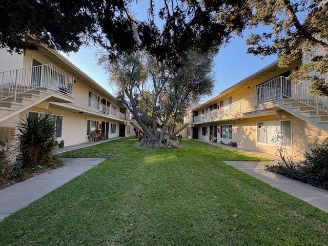 A tree in the middle of a grassy courtyard with apartment buildings in the background.