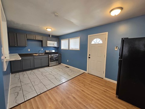 A kitchen with blue walls and wooden floors.
