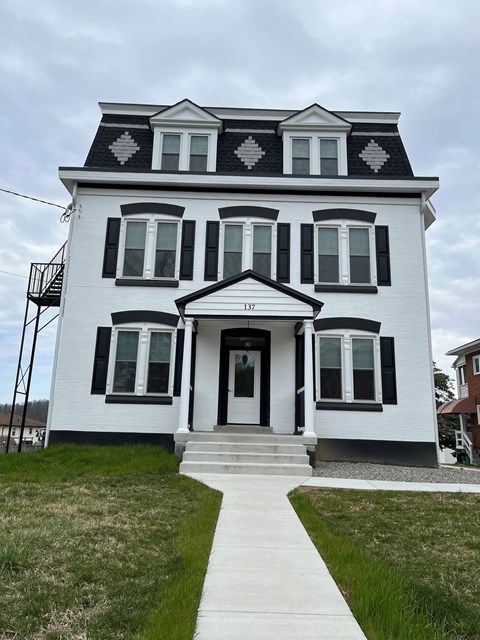 A white house with black shutters and a black and white patterned roof.