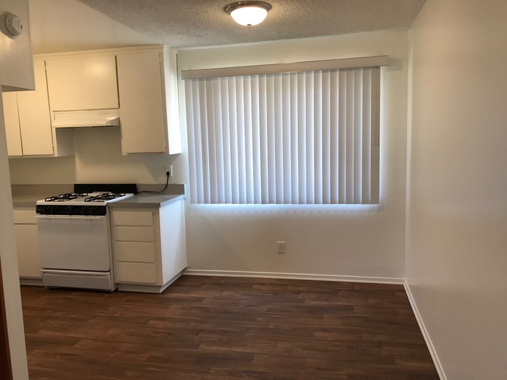 A kitchen with white cabinets and a stove top oven.