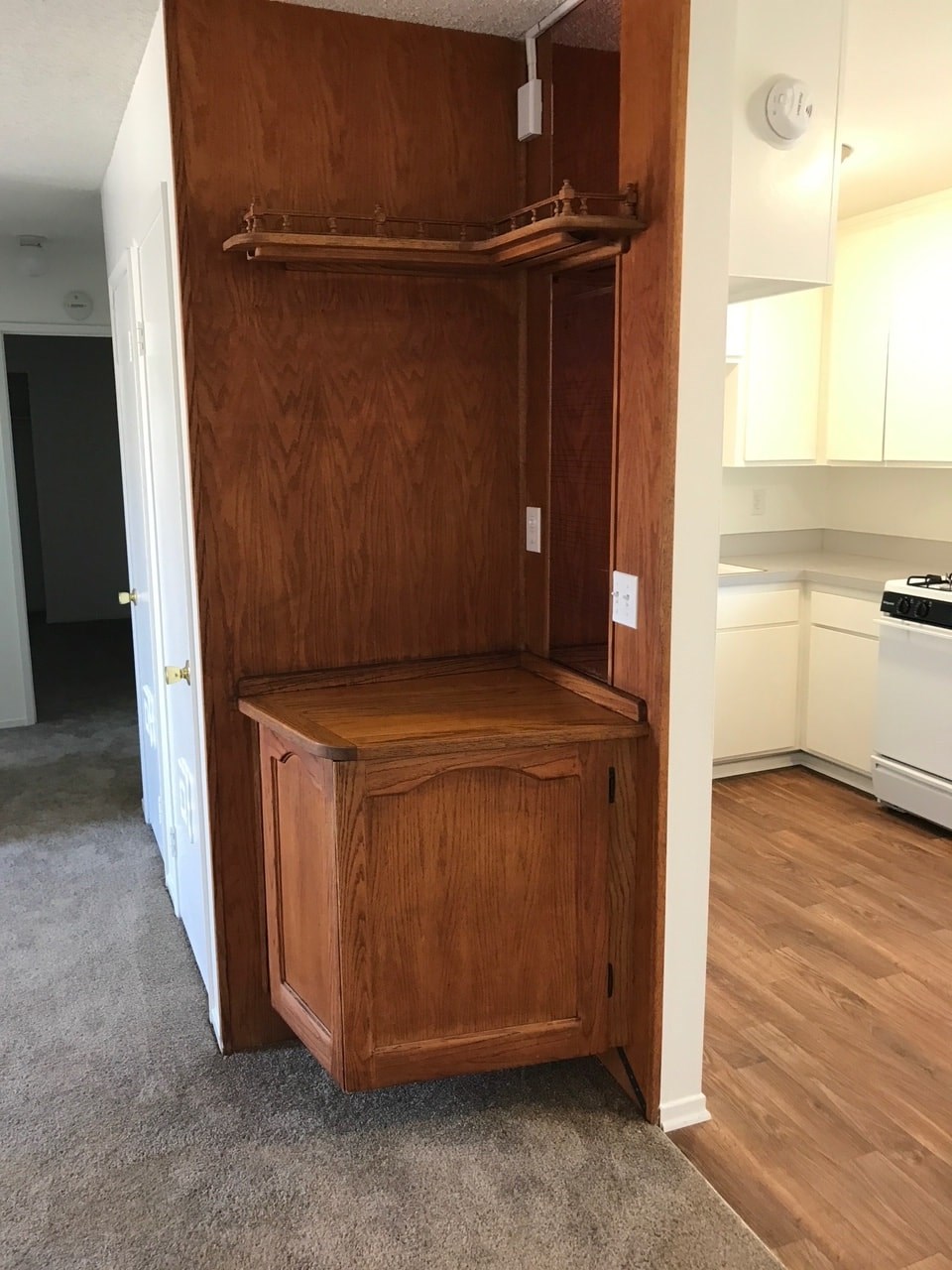 A wooden wardrobe with a shelf and a drawer is in a room.