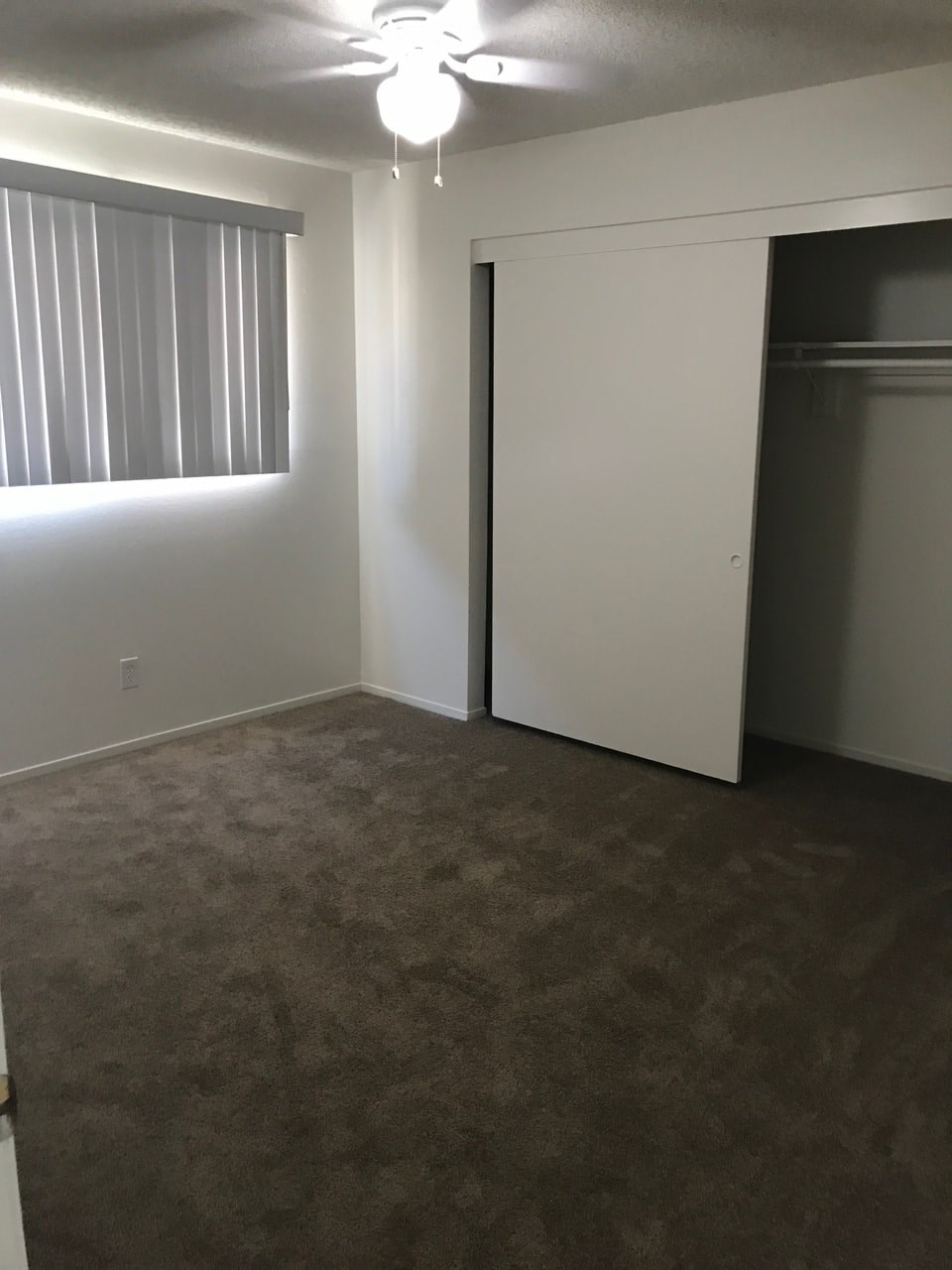 A room with a carpeted floor and a ceiling fan.