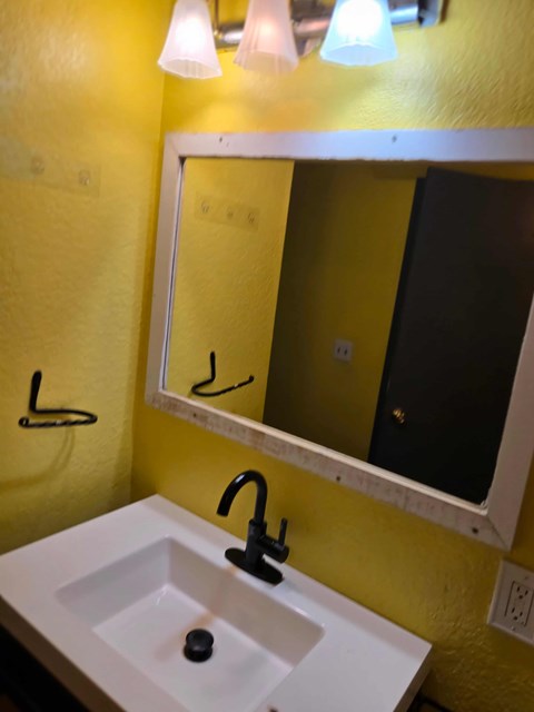 A bathroom with a yellow wall and a white sink.