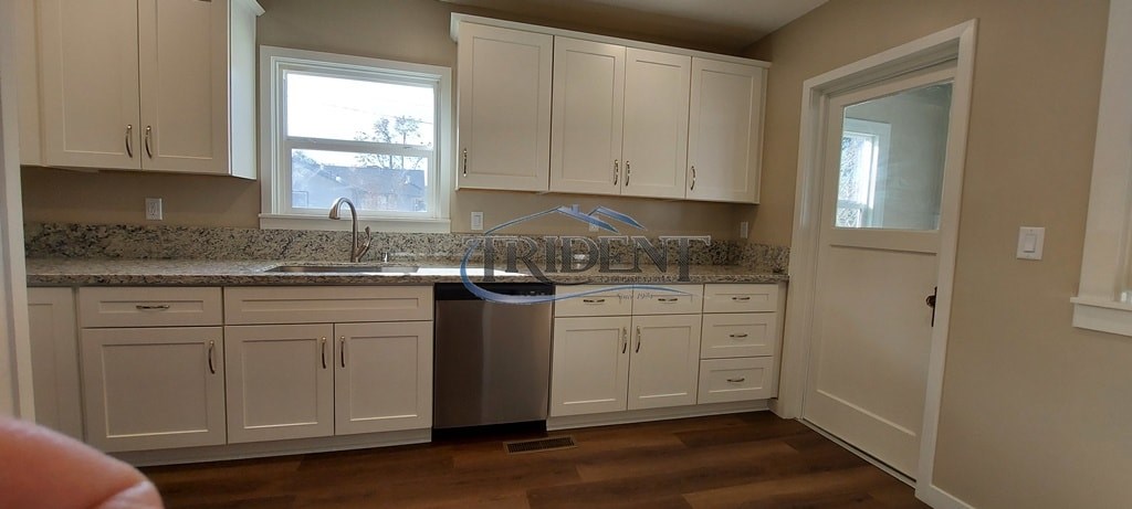 A kitchen with white cabinets and a granite countertop.