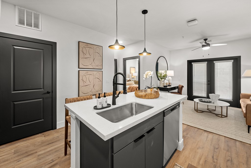 A modern kitchen with a black door, white countertop, and a ceiling fan.