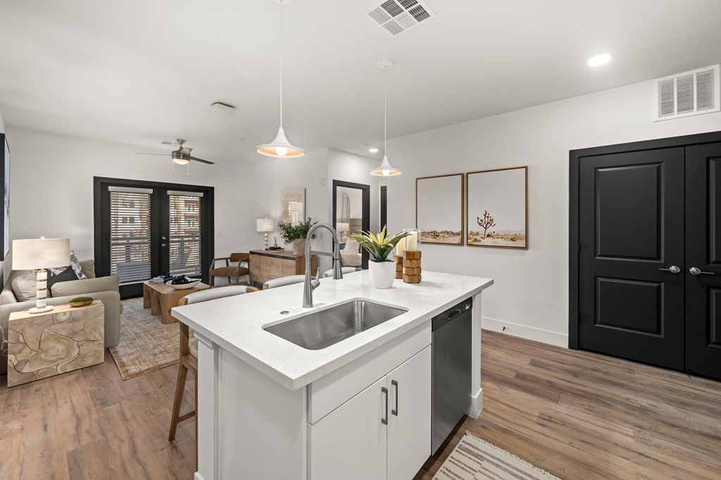 A modern kitchen with a white countertop and a black door.