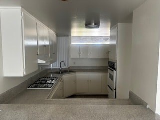 A kitchen with white cabinets and a stove top oven.