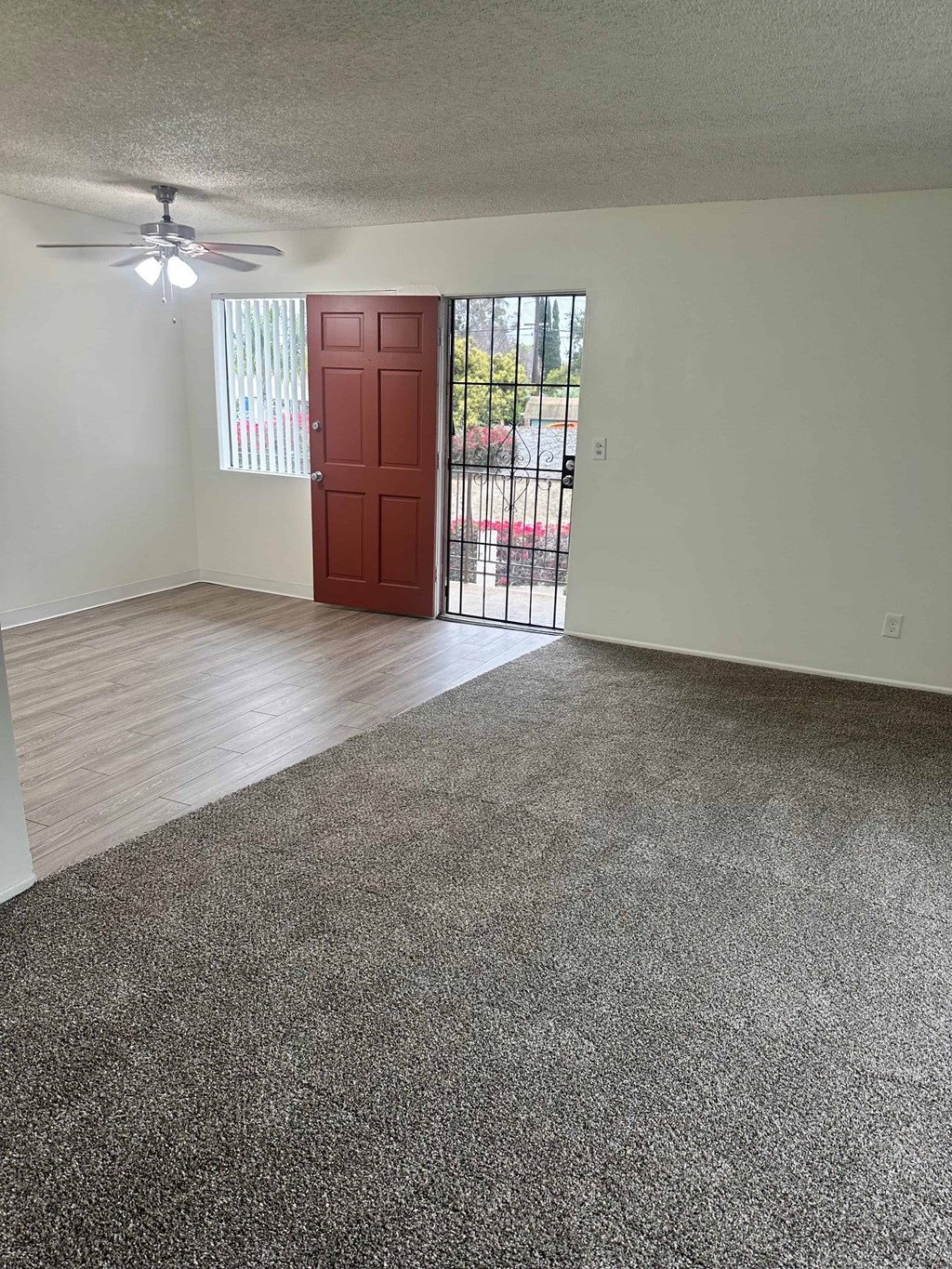 A room with a ceiling fan and a red door.