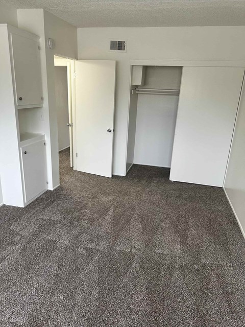 A carpeted room with a doorway leading to another room.