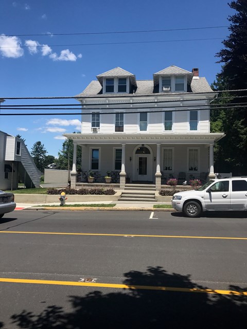 A white car is parked in front of a two-story house.