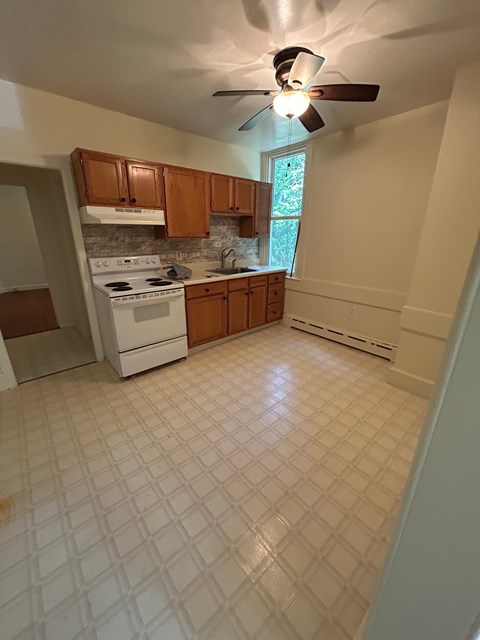 A kitchen with a white tile floor and a white stove top oven.