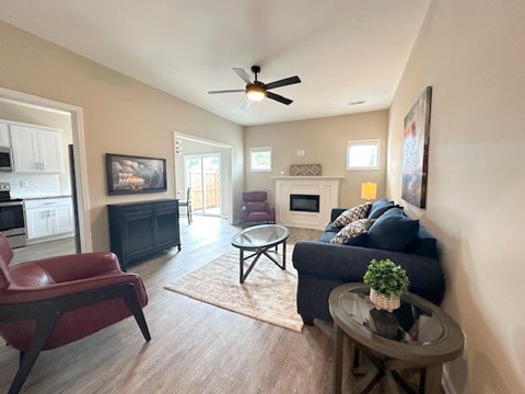 A living room with a red chair, a black couch, and a ceiling fan.