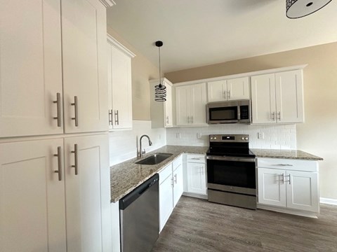 A kitchen with white cabinets and a granite countertop.