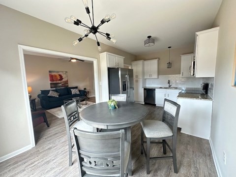 A kitchen with a table and chairs in the foreground and a living room in the background.