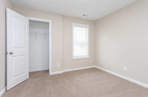 A room with a white door and a window with blinds.