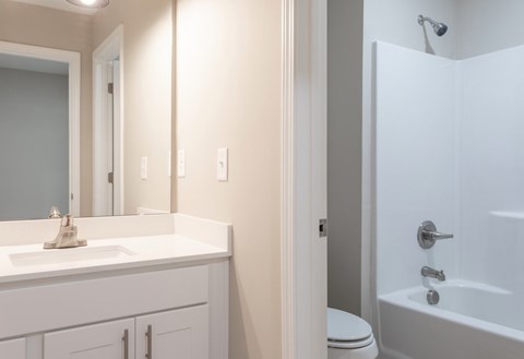 A white bathroom with a toilet, sink, and bathtub.