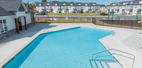 A blue swimming pool with a diving board and a small building next to it.