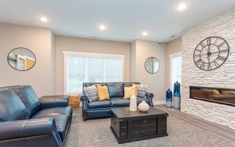A living room with a fireplace and a large clock on the wall.