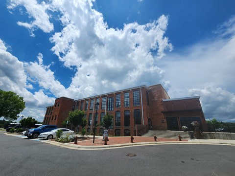 A large red brick building with a parking lot in front.