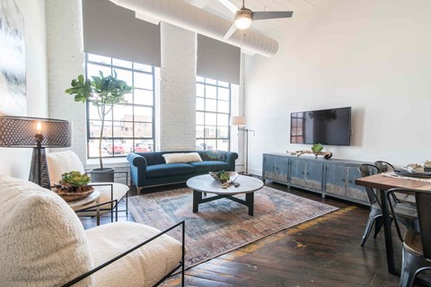 A living room with a blue couch and a television on a cabinet.