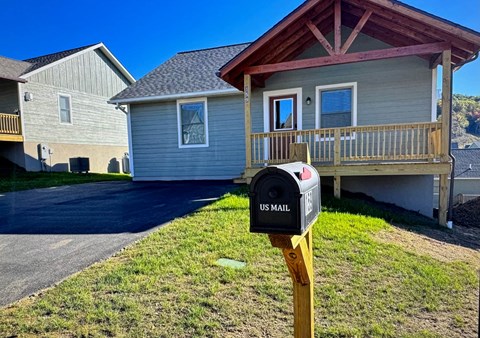 A US Mail mailbox stands in front of a house with a garage.