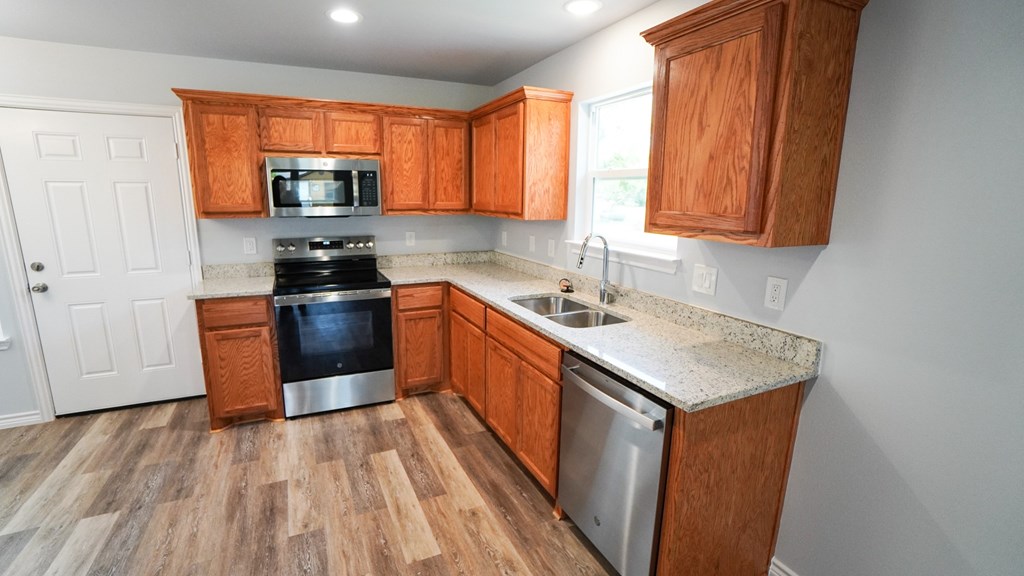 A kitchen with wooden cabinets and a stainless steel dishwasher.
