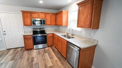 A kitchen with wooden cabinets and a stainless steel dishwasher.
