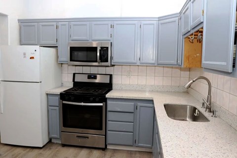 A kitchen with a white refrigerator, a microwave above the stove, and a sink with a faucet.