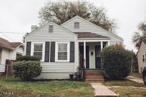 A small house with a front porch and a green door.