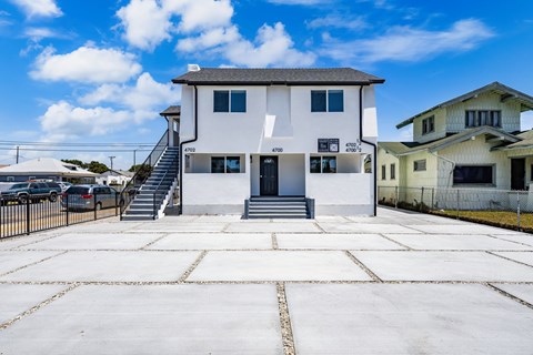 A white two-story house with a black door and windows.