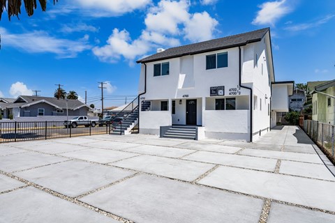 A white building with a black roof and a sign that reads "4700 12" is surrounded by a paved lot.